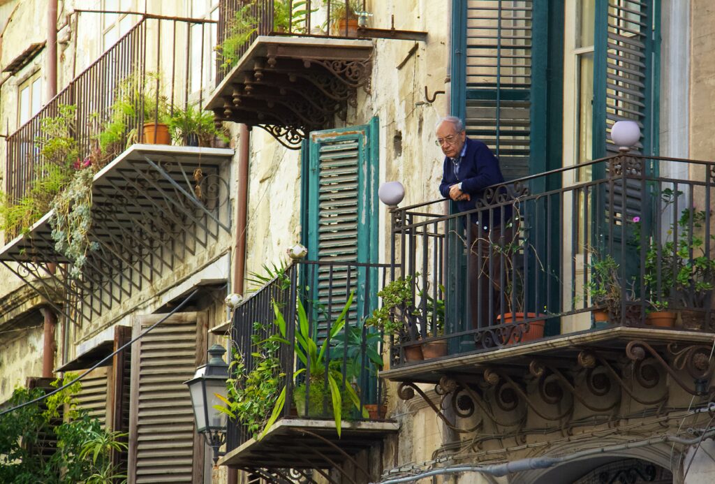 elderly man standing alone on a balcony